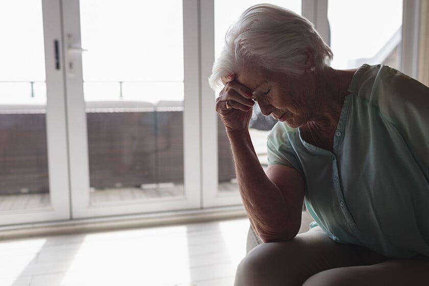 Side view of a worried senior woman sitting on a sofa